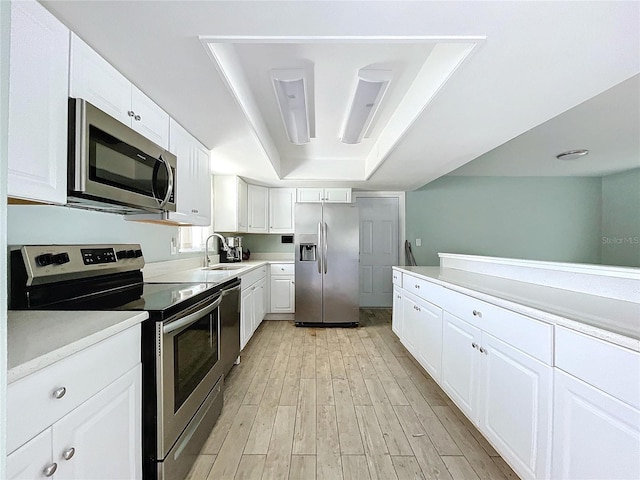 kitchen featuring light countertops, appliances with stainless steel finishes, a tray ceiling, and white cabinetry