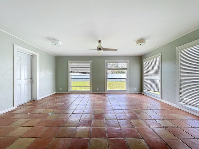 spare room featuring a textured wall, dark tile patterned floors, a ceiling fan, and baseboards