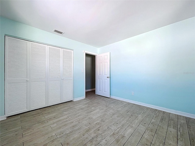 unfurnished bedroom with light wood finished floors, a closet, visible vents, and baseboards