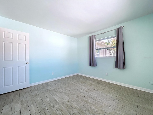 empty room featuring light wood-type flooring and baseboards