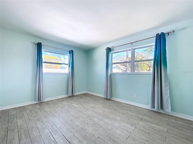 spare room featuring light wood finished floors and baseboards