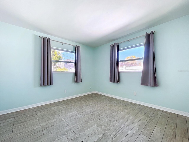 unfurnished room with a wealth of natural light, light wood-style flooring, and baseboards