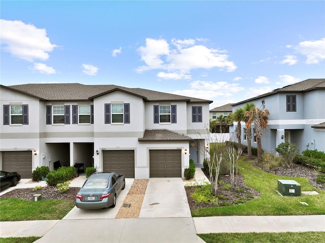 multi unit property with an attached garage, driveway, a shingled roof, and stucco siding