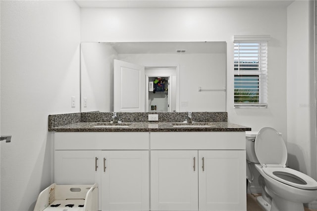 bathroom with visible vents, a sink, toilet, and double vanity