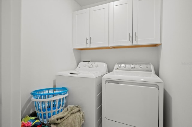 washroom featuring cabinet space and washer and clothes dryer