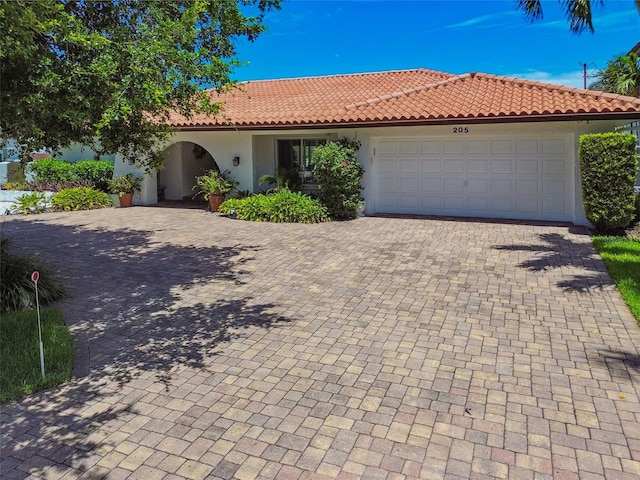 view of front of property with an attached garage, a tile roof, decorative driveway, and stucco siding