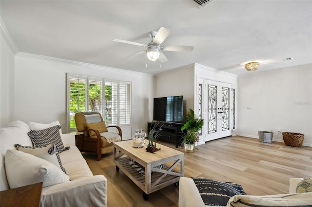 living area featuring baseboards, light wood-type flooring, a ceiling fan, and crown molding