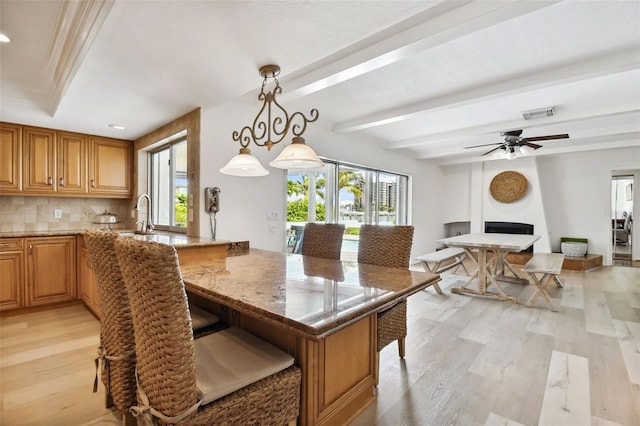 dining space with a wealth of natural light, beam ceiling, a fireplace, and light wood finished floors