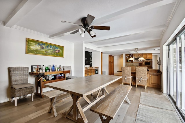 dining area with light wood finished floors, crown molding, a ceiling fan, and beamed ceiling