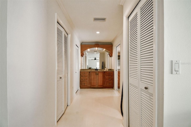 hallway featuring arched walkways, ornamental molding, and visible vents