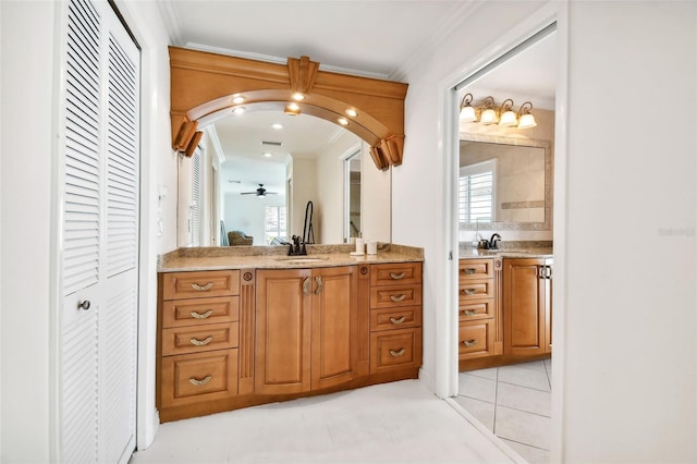 bathroom with crown molding, a closet, two vanities, a sink, and tile patterned floors