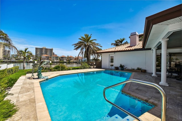 outdoor pool with a water view and a patio area