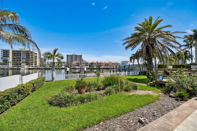 view of home's community with a lawn, a water view, and a boat dock