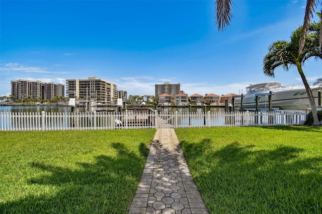 view of dock featuring a yard, a water view, and fence