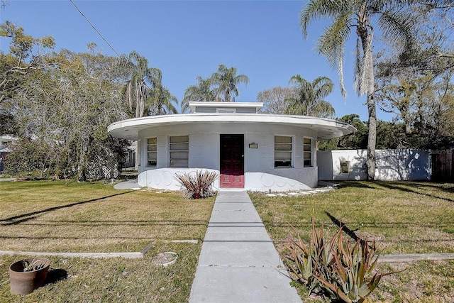 view of front of house with a front lawn, fence, and stucco siding