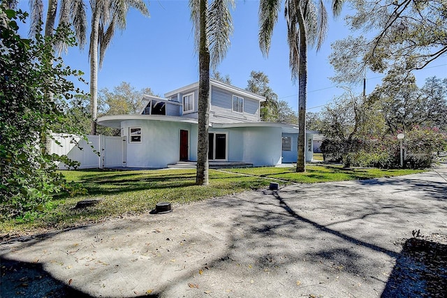 back of house with a lawn, fence, a gate, and stucco siding