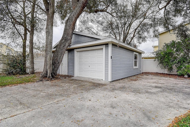 garage with concrete driveway and fence