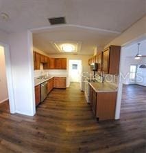 kitchen with brown cabinetry, light countertops, visible vents, and stainless steel dishwasher