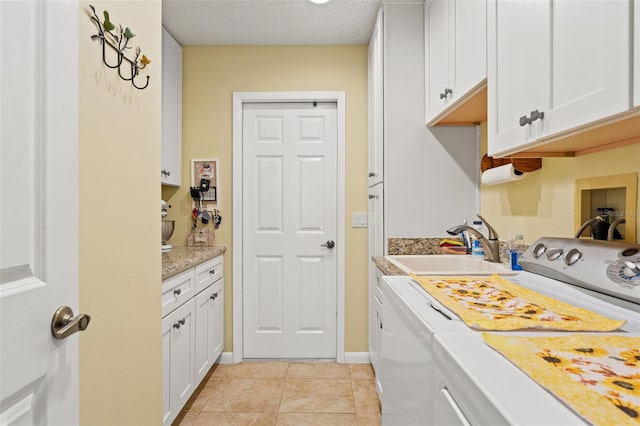 laundry room with light tile patterned flooring, sink, cabinets, washing machine and clothes dryer, and a textured ceiling