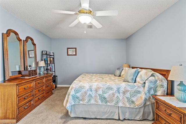 bedroom with ceiling fan, carpet floors, and a textured ceiling