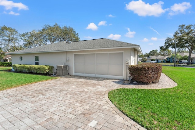 view of side of property with a garage, cooling unit, and a lawn