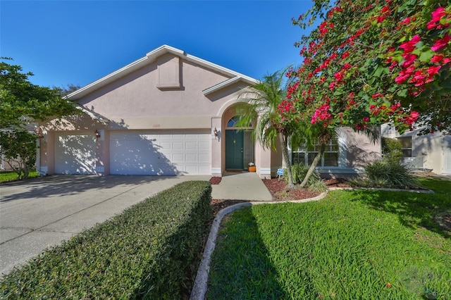 view of front of property featuring a garage, a front yard, driveway, and stucco siding