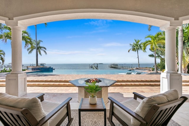 view of patio / terrace with a hot tub, an infinity pool, and a water view