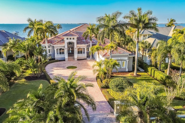 view of front of property with decorative driveway, stucco siding, a tiled roof, and a water view