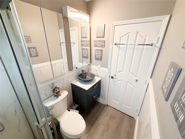 bathroom with toilet, hardwood / wood-style flooring, tile walls, and vanity