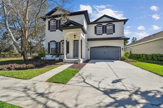 traditional home with driveway, a garage, and stucco siding