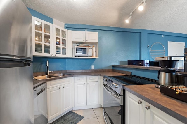 kitchen featuring white cabinetry, sink, light tile patterned floors, stainless steel appliances, and a textured ceiling