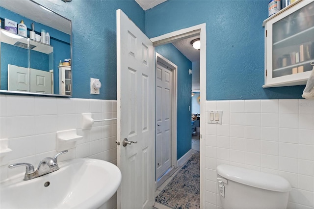 bathroom with tile walls, sink, and toilet