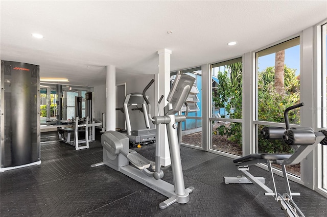 gym featuring expansive windows, a textured ceiling, and ornate columns