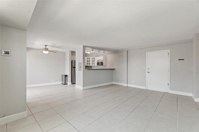 3315 58th Ave S Unit 314, Saint Petersburg, FL 33712 - unfurnished living room with a textured ceiling, light tile patterned floors, ceiling fan, and baseboards