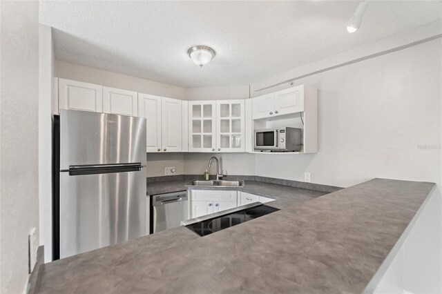3315 58th Ave S Unit 314, Saint Petersburg, FL 33712 - kitchen with stainless steel appliances, a sink, dark countertops, glass insert cabinets, and white cabinetry