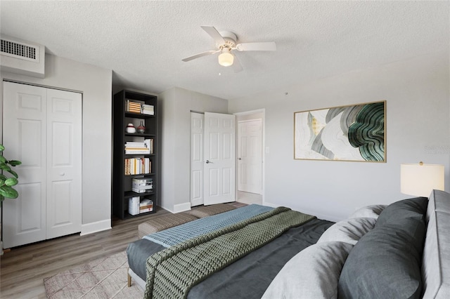 3315 58th Ave S Unit 314, Saint Petersburg, FL 33712 - bedroom with multiple closets, wood finished floors, a textured ceiling, baseboards, and a ceiling fan