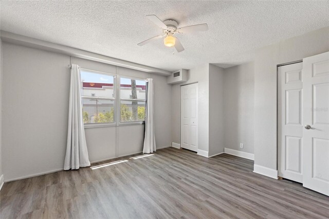3315 58th Ave S Unit 314, Saint Petersburg, FL 33712 - unfurnished bedroom featuring wood finished floors, a textured ceiling, baseboards, and a ceiling fan