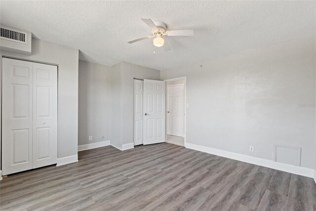 3315 58th Ave S Unit 314, Saint Petersburg, FL 33712 - unfurnished bedroom featuring wood finished floors, a textured ceiling, baseboards, multiple closets, and a ceiling fan