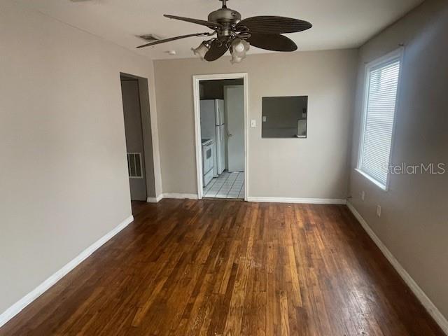 unfurnished room featuring ceiling fan, dark hardwood / wood-style floors, and a wealth of natural light