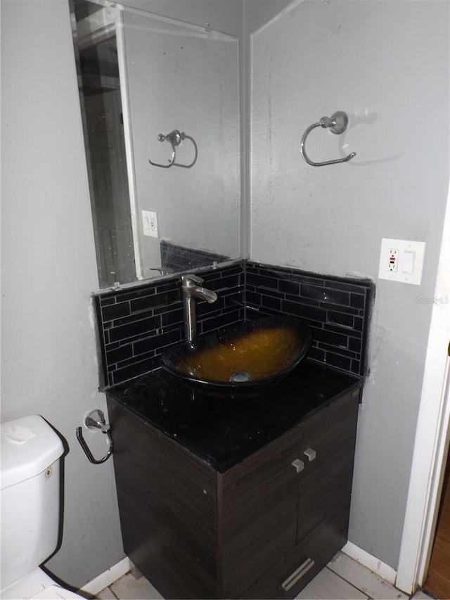 bathroom featuring toilet, backsplash, and vanity