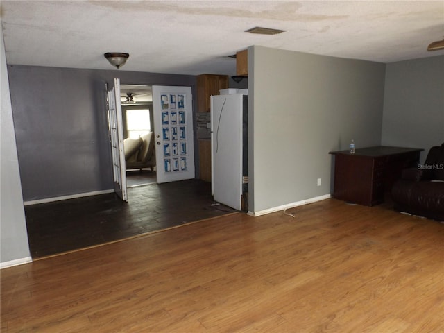 unfurnished living room featuring a ceiling fan, wood finished floors, visible vents, and baseboards