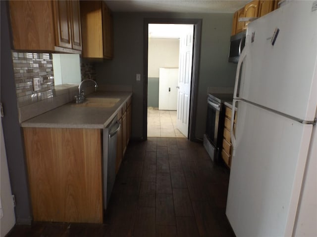 kitchen featuring stainless steel appliances, dark wood-style flooring, a sink, light countertops, and backsplash