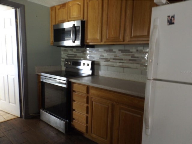 kitchen featuring stainless steel appliances, brown cabinetry, light countertops, and decorative backsplash