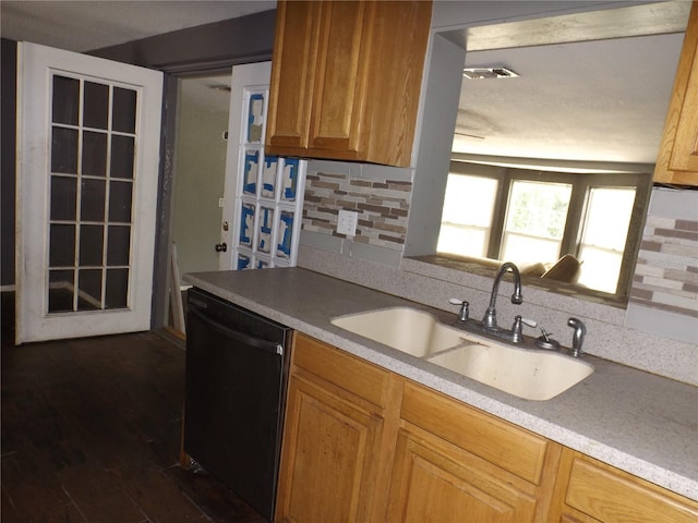 kitchen featuring black dishwasher, dark wood-style flooring, a sink, light countertops, and backsplash
