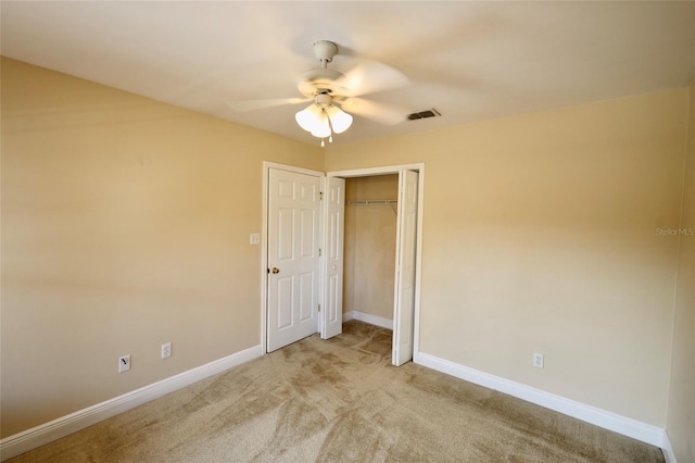 unfurnished bedroom with ceiling fan, light carpet, and a closet