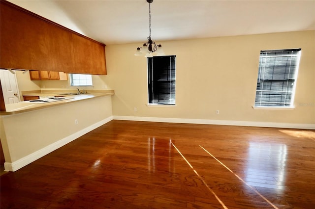 unfurnished dining area with a notable chandelier, vaulted ceiling, sink, and dark hardwood / wood-style floors