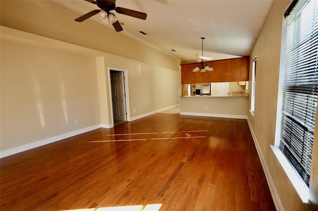 unfurnished living room featuring dark hardwood / wood-style flooring, ceiling fan with notable chandelier, and lofted ceiling