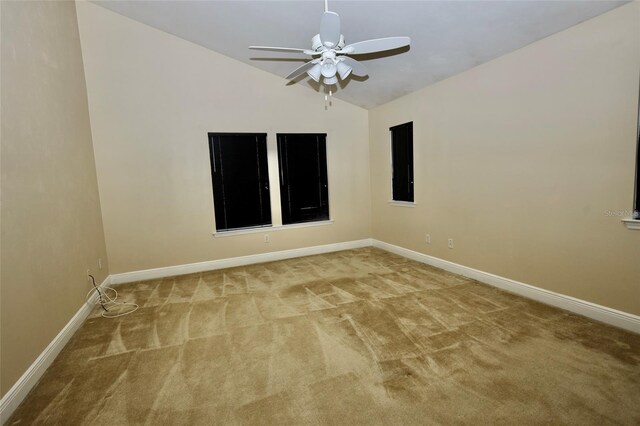 empty room with lofted ceiling, ceiling fan, and light colored carpet