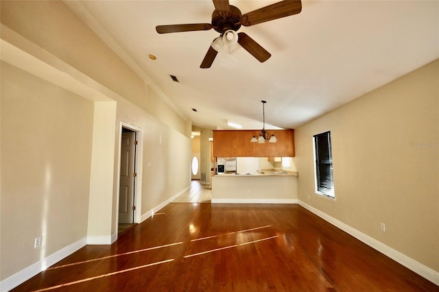 unfurnished living room featuring lofted ceiling, dark hardwood / wood-style floors, and ceiling fan with notable chandelier