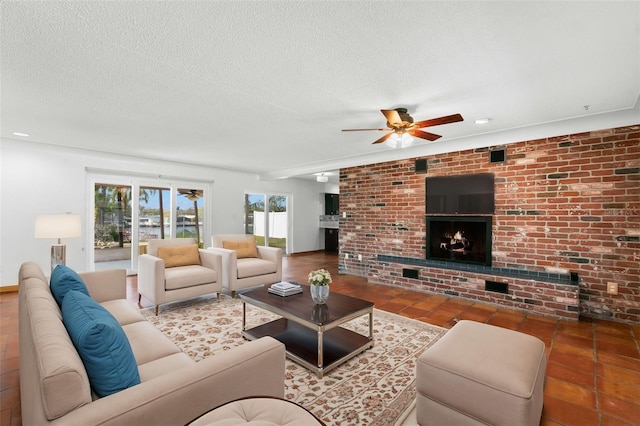 living room with ceiling fan, a textured ceiling, and a fireplace